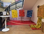 Ausstellung zum 50-jährigen Schuljubiläum mit farbigen Kunstwerken auf Staffeleien, rotem Teppich und einer goldenen 50 als Dekoration.
