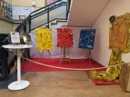 Ausstellung zum 50-jährigen Schuljubiläum mit farbigen Kunstwerken auf Staffeleien, rotem Teppich und einer goldenen 50 als Dekoration.